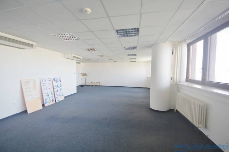 A spacious office with a blue carpet, windows, and air conditioning, suitable for various uses.