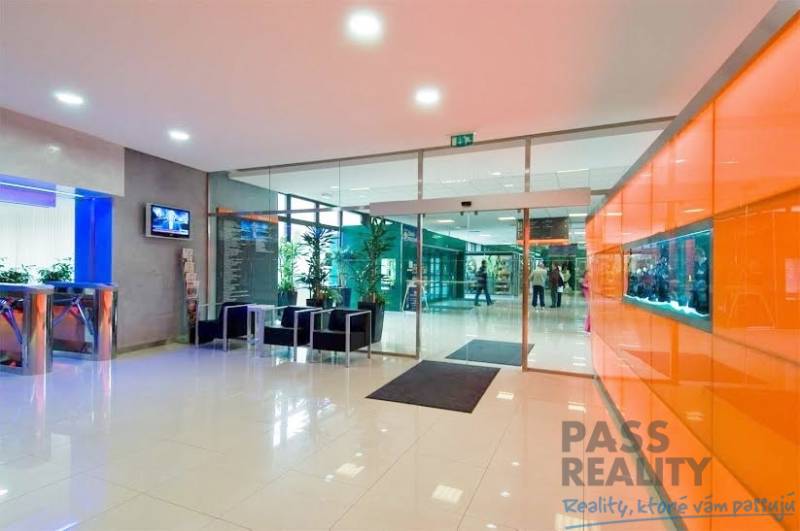 Office lobby with white glossy floor, orange wall, and glass doors.
