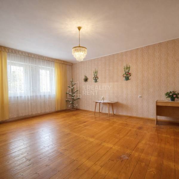Interior of a family house with wood-patterned flooring, a chandelier, and decorative wallpaper.