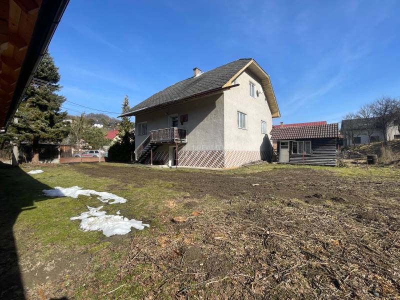 A family house in Terchová with a large yard and a shelter, surrounded by grass and trees.