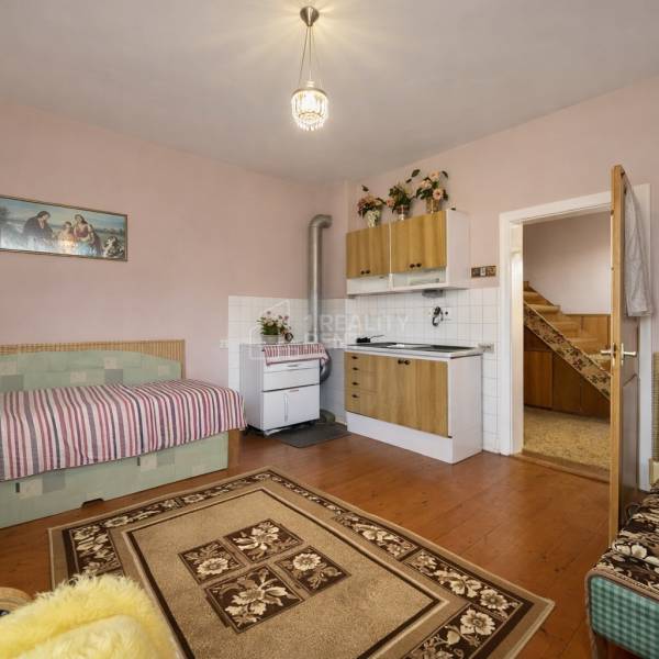 A room with a kitchen unit, sofa, stove, and wooden decor flooring in a family house.