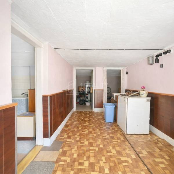 A hallway in a family house with a wooden decor floor, cabinets, and doors leading to the bathroom.