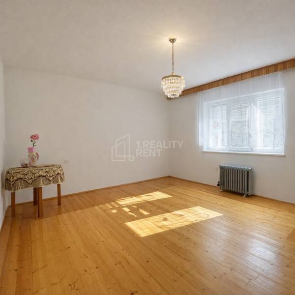 A spacious room in a family house with a wooden decor floor and an elegant chandelier.
