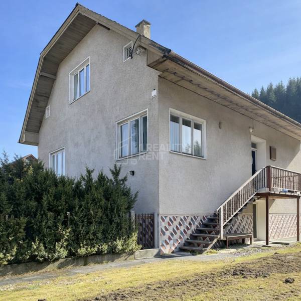 A family house in Terchová with large windows, a staircase, and a well-maintained front garden.