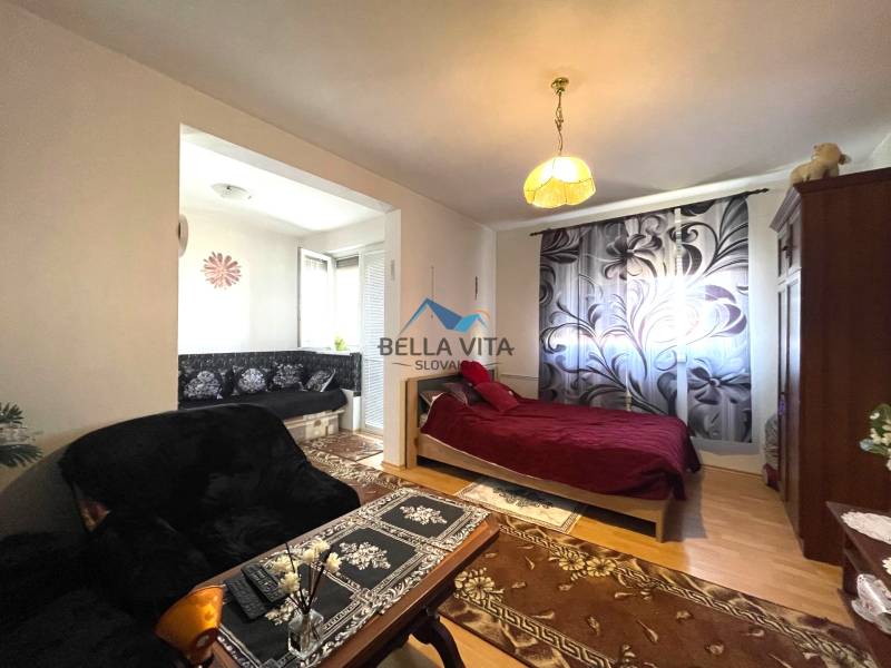 Cozy 1-room apartment with a wooden-patterned floor, a bed, and a sofa with a floral pattern.