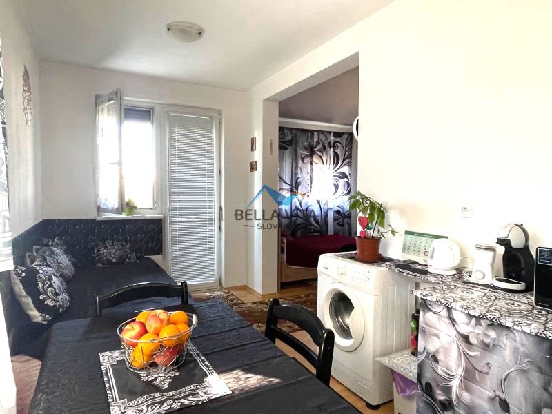 A kitchen in a studio apartment with a washing machine, table, and decor on the table.