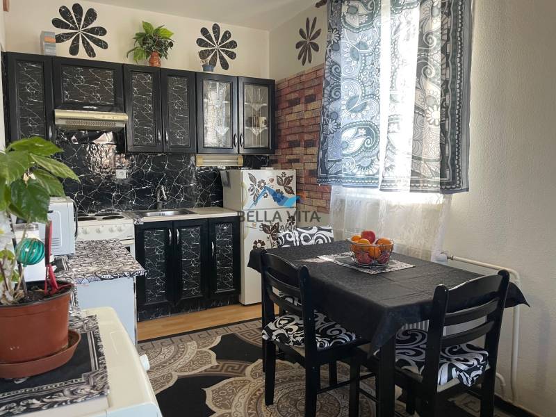 A kitchen with tables, black cabinets, and patterned curtains in a studio apartment.