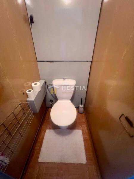 A toilet in a 3-room apartment with wooden decor and storage solutions.