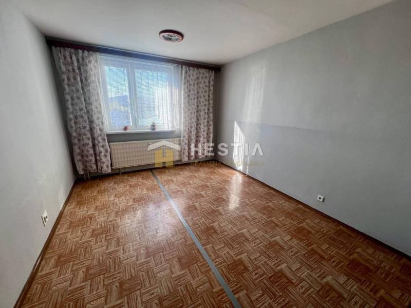 A room in a 3-room apartment with a wooden decor floor and light gray walls.