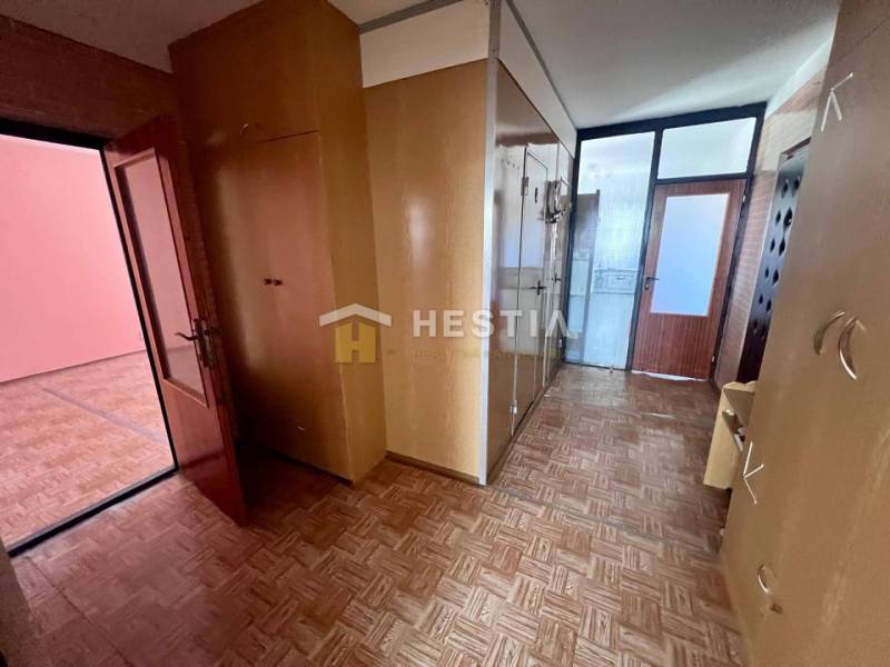 Hallway of a 3-room apartment with wooden decor, built-in wardrobes, and glass doors.