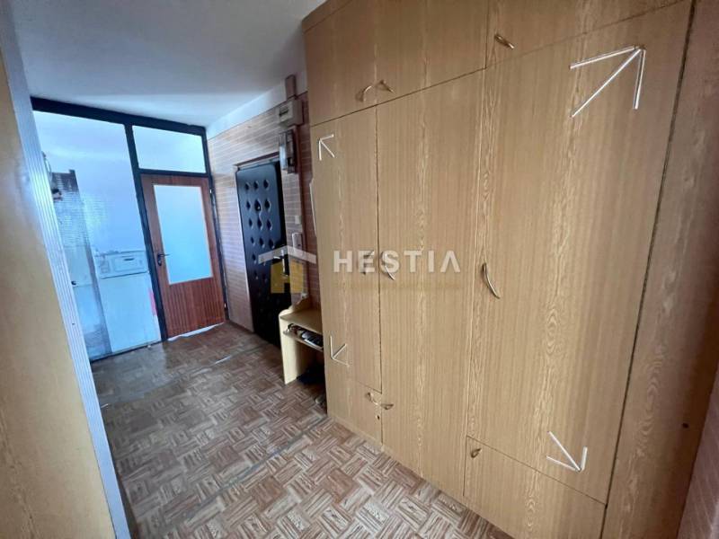 A hallway in a 3-room apartment with a wardrobe and a floor with a wood decor.