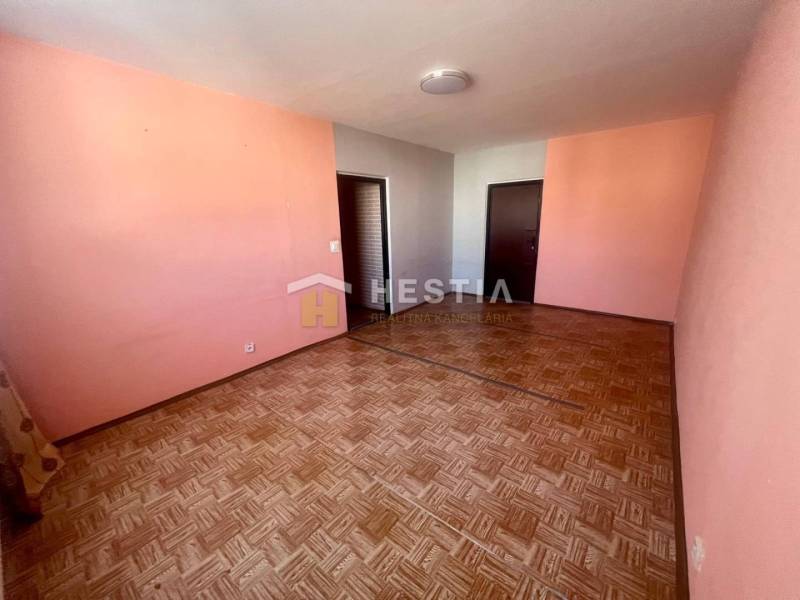 A room in a 3-room apartment with pink walls and a wooden decor floor.