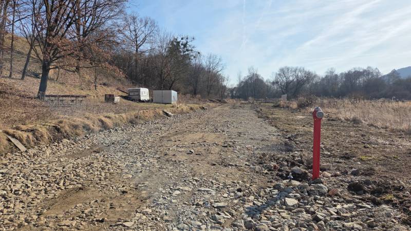 Lands - housing in Haniska, a rocky road between trees and a container.