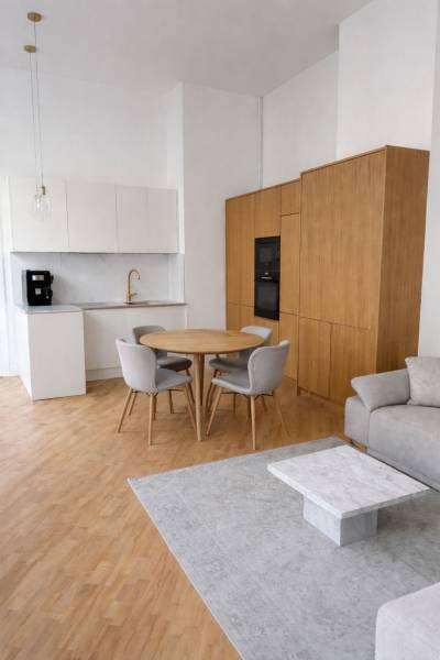 A kitchen in a 3-room apartment with a wood-patterned floor, a gray carpet, and a dining table.