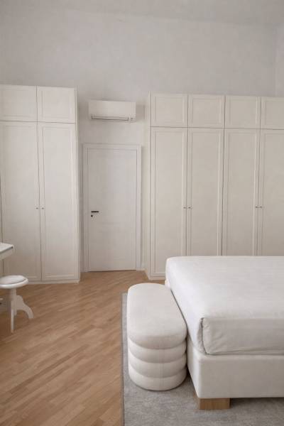 Bedroom with white wardrobes, bed, wood-decorated flooring, and air conditioning in a 3-room apartment.
