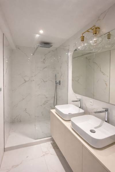 A bathroom in a 3-room apartment with white ceramic tiles and two sinks.