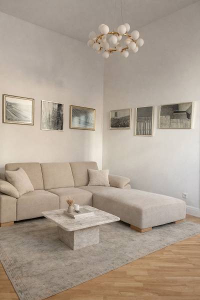 Living room in a 3-room apartment with a beige sofa, table, paintings, and a floor with a wooden decor.