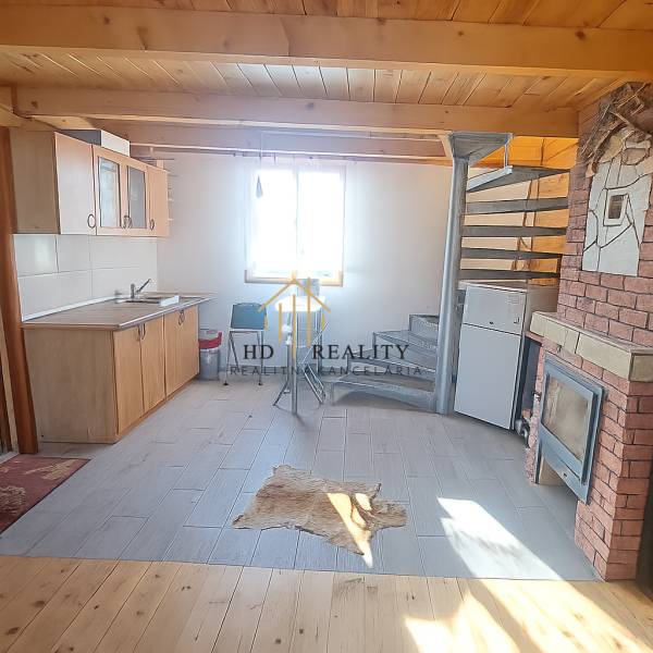 A cottage with a kitchen, spiral staircase, and wood-patterned flooring.
