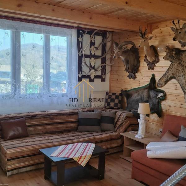 Interior of a cabin with trophies, wooden paneling, and a floor with wood decor.
