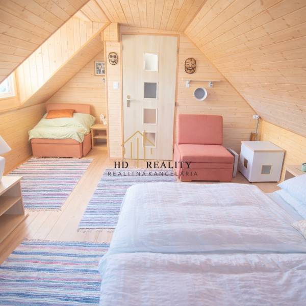 Wooden interior of the cabin with a wood-patterned floor, bed, and chair.
