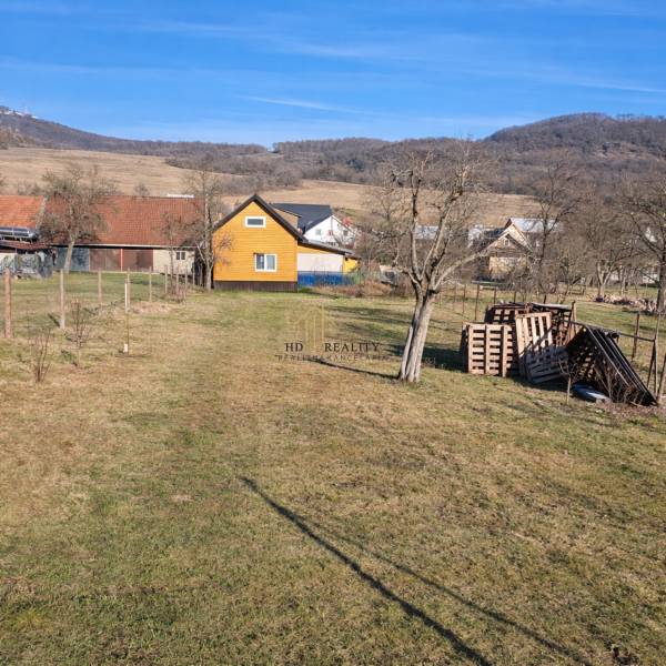 The yard of the cottage in Kráľovce Krnišov with fruit trees and mountains in the background.