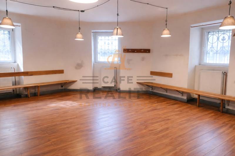 Commercial space with walls, benches, and floor with wooden decor, illuminated by pendant lamps.