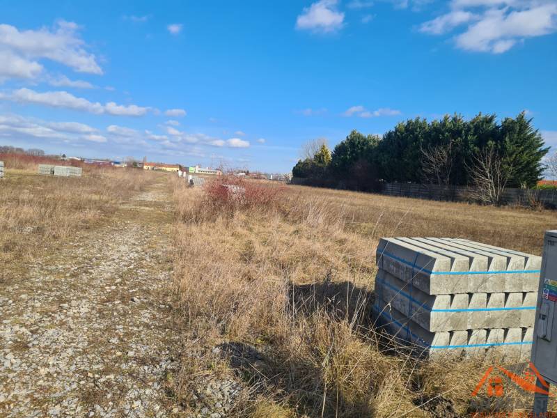Plots - housing in Nové Zámky, gravel road, greenery, blue sky, and building materials.