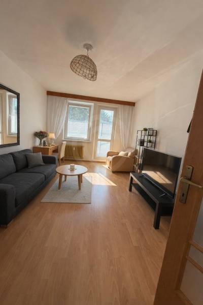Living room in a three-room apartment with a wooden decor floor and comfortable furniture.