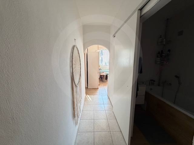 A hallway with tiles in a 3-room apartment with wall decorations and a view into the bathroom.