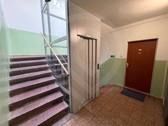 The apartment building has stairs, an elevator, and the door to a 3-room apartment.