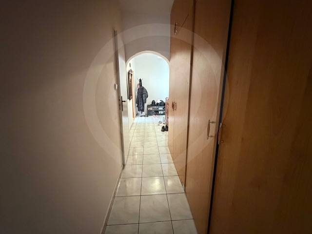 A narrow hallway with tiled flooring and built-in wardrobes leading to the living area of a 3-room apartment.