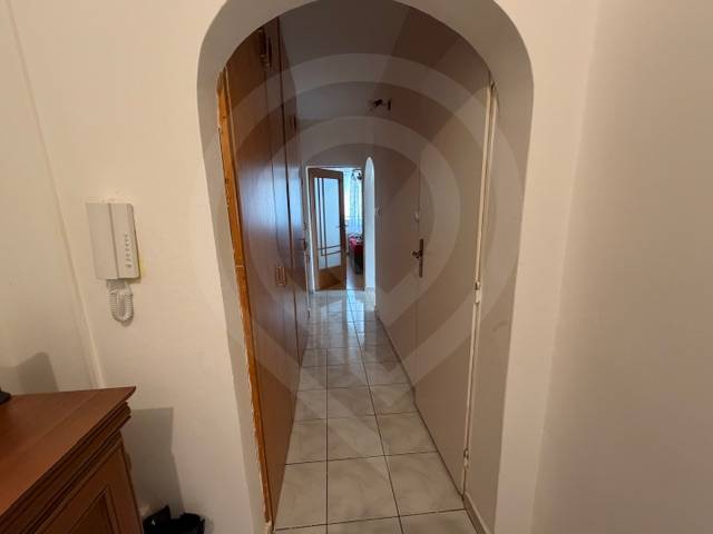 A hallway with light tiles, an arched passageway, and a wardrobe in a 3-room apartment.