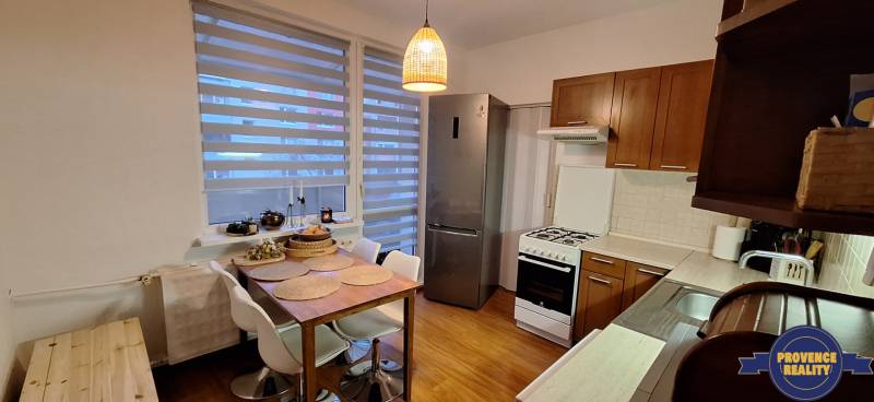 A kitchen with a stove, refrigerator, and a wooden decor floor in a 4-room apartment.