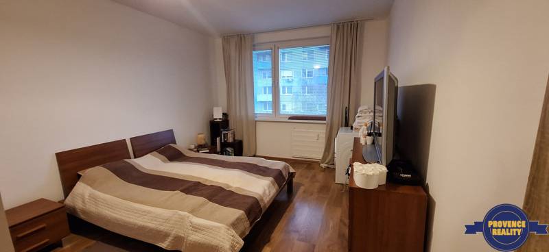 A bedroom in a 4-room apartment with a wooden decor floor and a large bed.