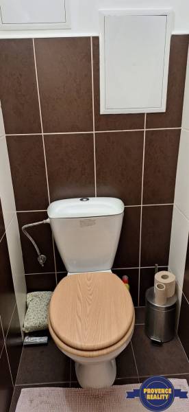 A toilet with a wooden decor floor in a 4-room apartment.