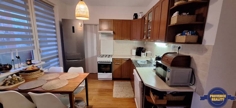 A kitchen with a wooden decor floor, dining table, appliances, bright interior in a 4-room apartment.