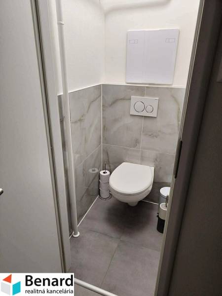 A toilet with tiles and a wall-hung toilet in a 2-room apartment.