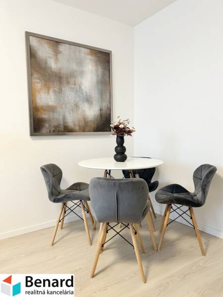 Dining area with four gray chairs and a table in a 2-room apartment.