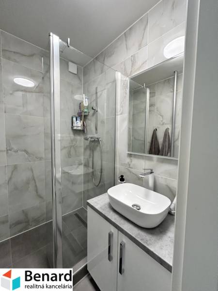 A modern bathroom in a 2-room apartment with a spacious shower and a sink.