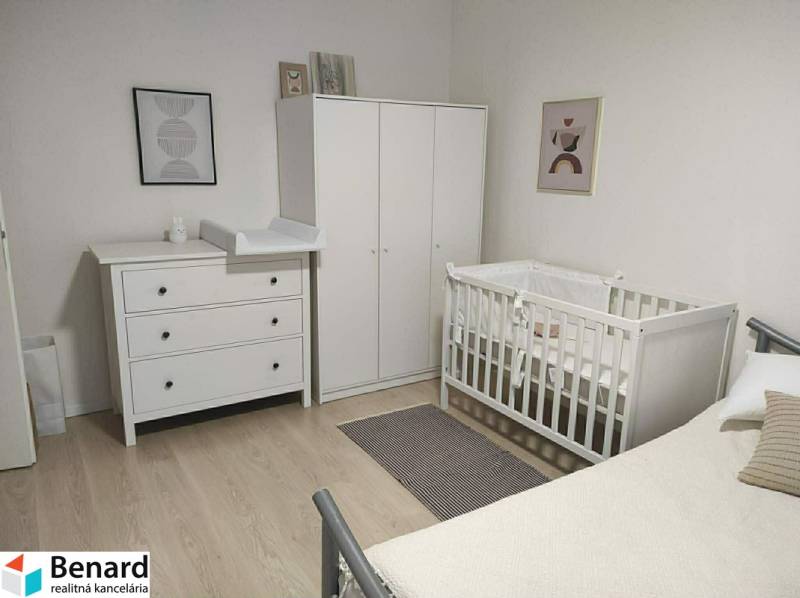 Children's room with white furniture and a wooden decor floor in a 2-room apartment.