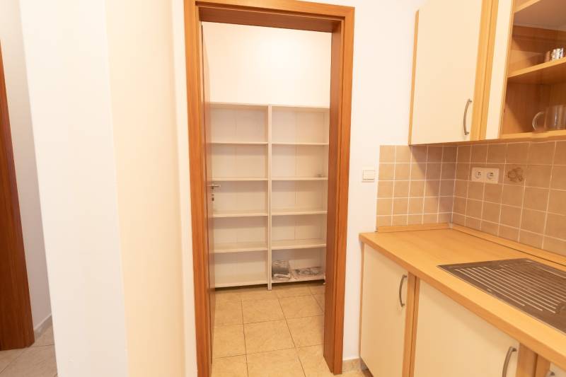 A kitchen in a 2-room apartment with shelves and tiles, cabinets with a wooden decor.