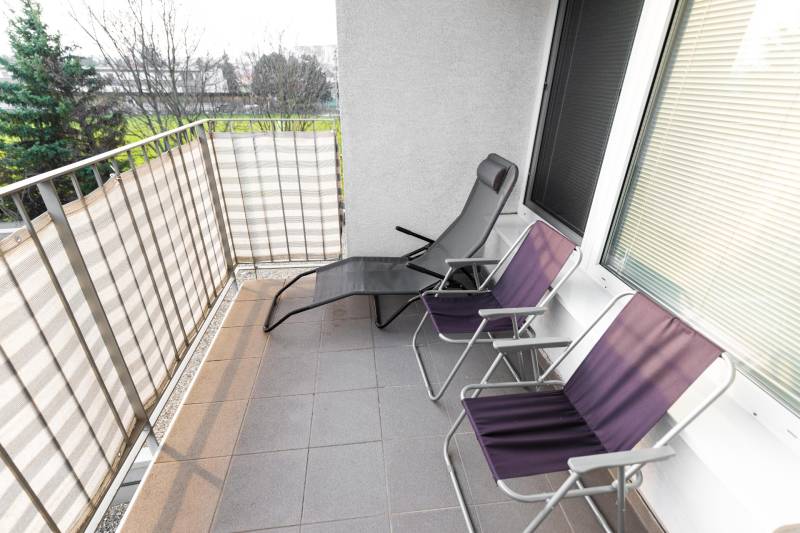 Balcony of a 2-room apartment with metal railing and three folding chairs on Hrachova Street, Bratislava - Ružinov.