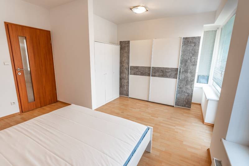 Bedroom with a bed, wardrobe, and wooden decor flooring in a 2-room apartment.