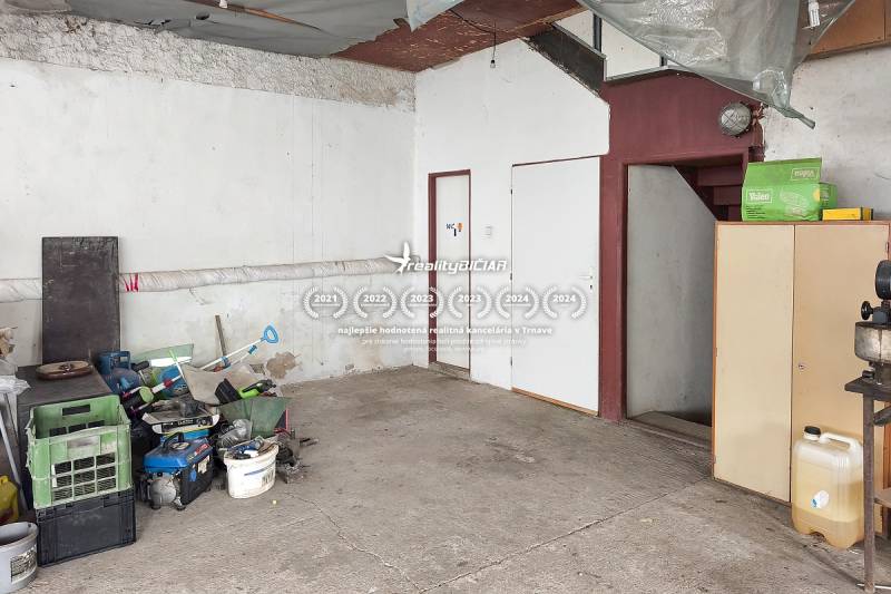 A garage in a family house, stored tools, concrete floor, stairs, and white furniture.