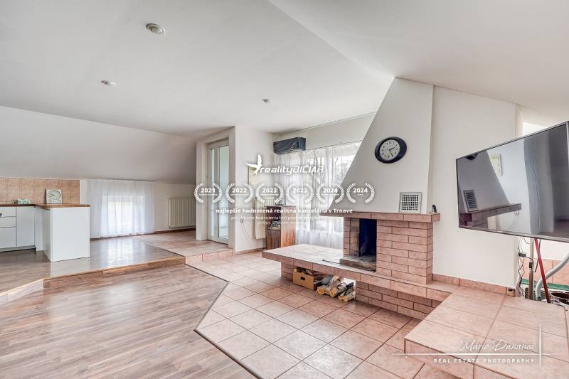 Living room with a fireplace in a family house, floor with wooden decor, spacious windows.