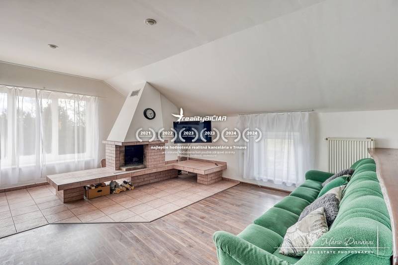 Living room with a fireplace, green sofa, and wood-patterned flooring in a family house.