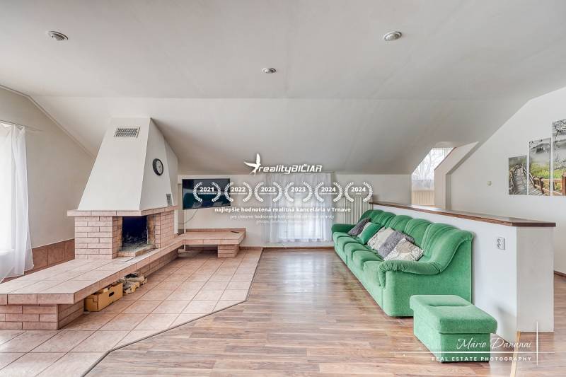 Living room in a family house with a fireplace, green sofa, and wooden decor flooring.