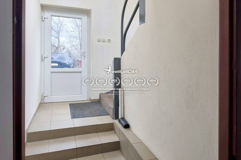 The entrance hallway of a family house with a tiled floor and white walls.