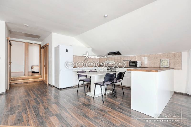 A kitchen with a dining table and appliances in a family house, with a wooden decor floor.