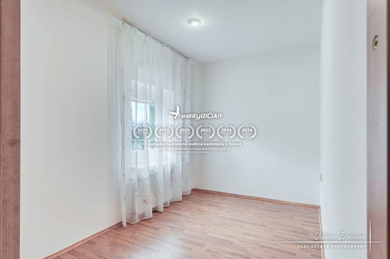 A bright room with a wood-patterned floor and curtains in a family house.